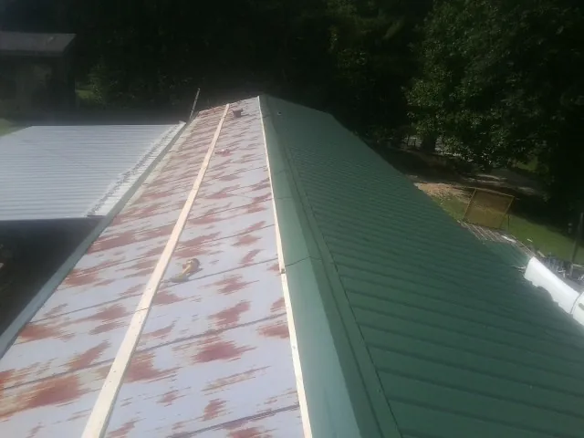Old rusted panels beside newly installed green metal roofing — Wind Damage Roof Repair by Roofing Brothers in Kewanee