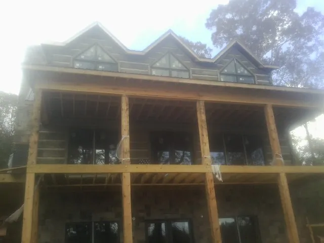 Dormers and porch framing on a large log home under construction — Roof Coating work by our crew in Kewanee