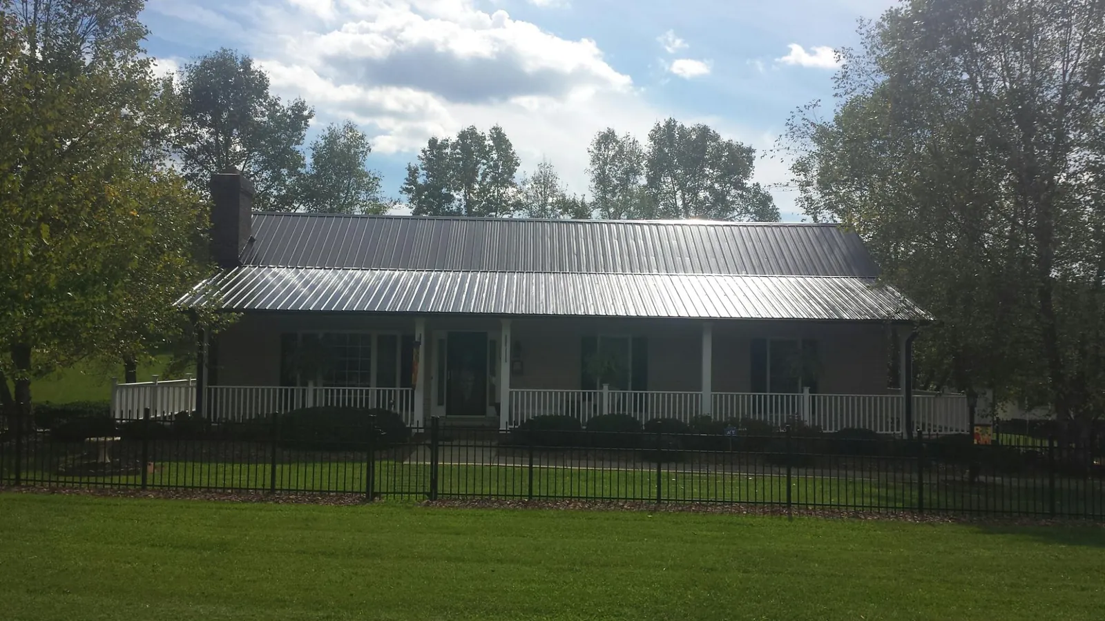 Gray metal roof on a brick ranch with a full width front porch — Gutter Guard Installation work by our crew in Kewanee