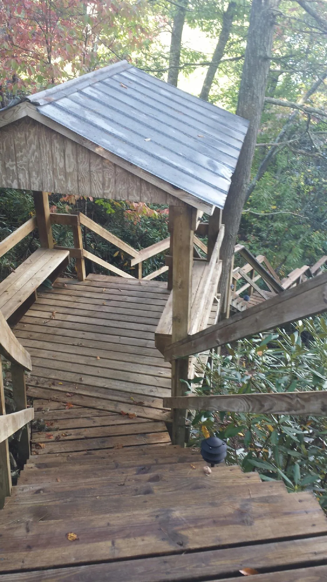 Metal roofed shelter over wooden steps on a wooded walkway — Skylight Repair & Installation work by our crew in Kewanee