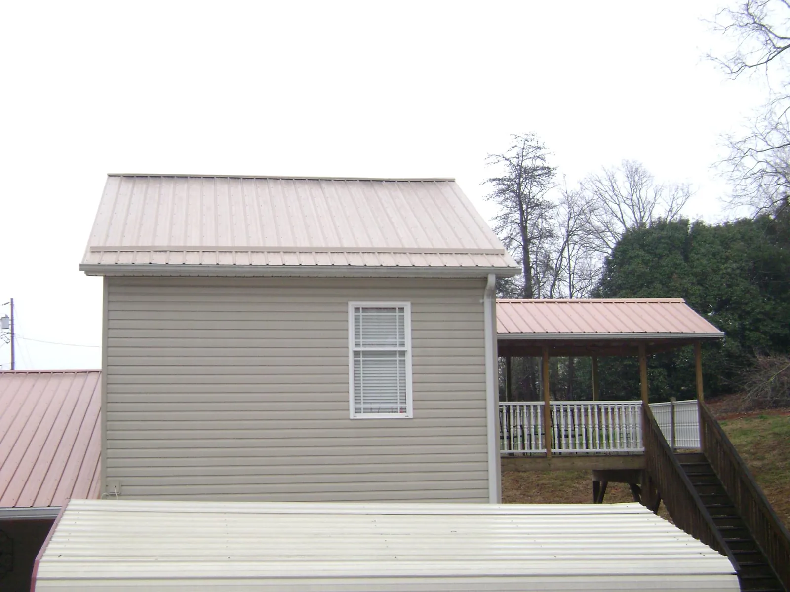 Tan metal roofs on a two story addition and attached porch, from a Roof Replacement job in Kewanee