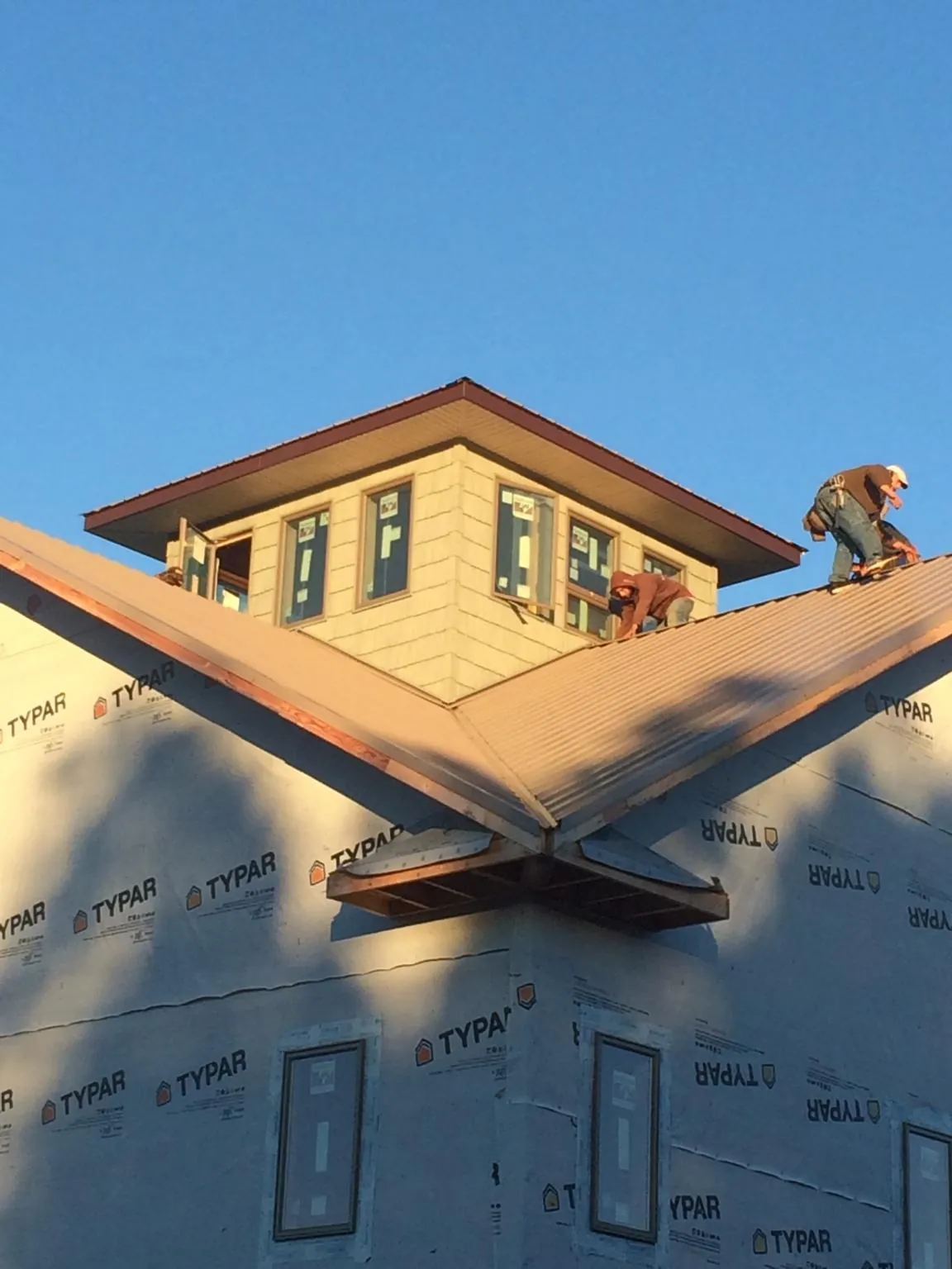 Roofers working around a rooftop cupola on a new metal roof at sunset — Roof Waterproofing in Kewanee by Roofing Brothers